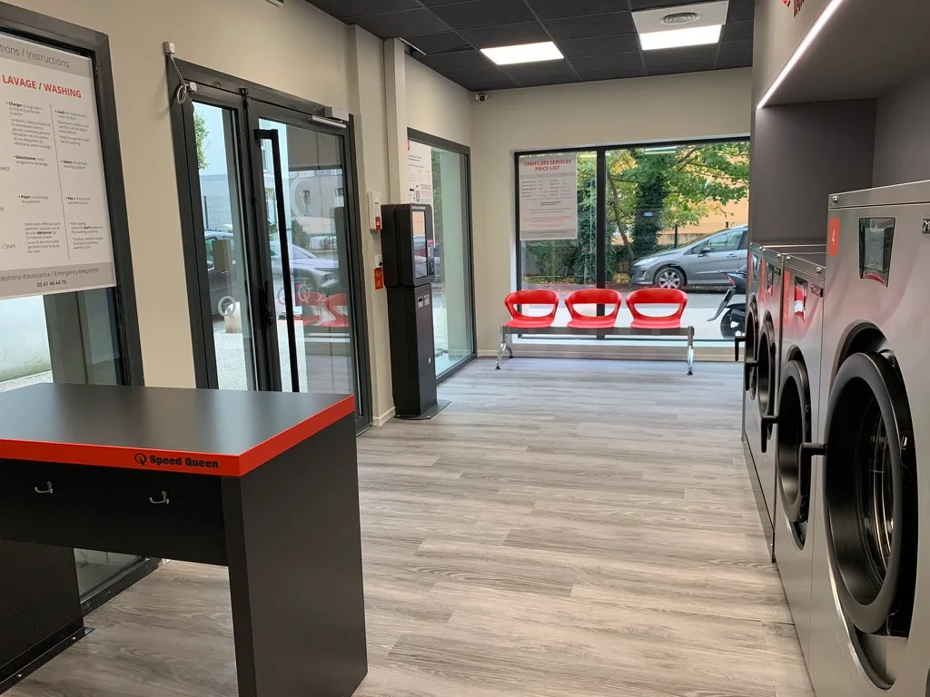 Espace client avec table de pliage et instructions, laverie Croix-Daurade Toulouse